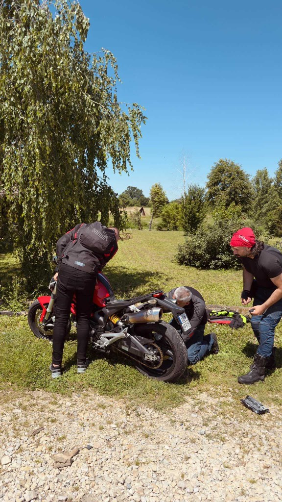 Riders helping fix a motorcycle at a roadside stop